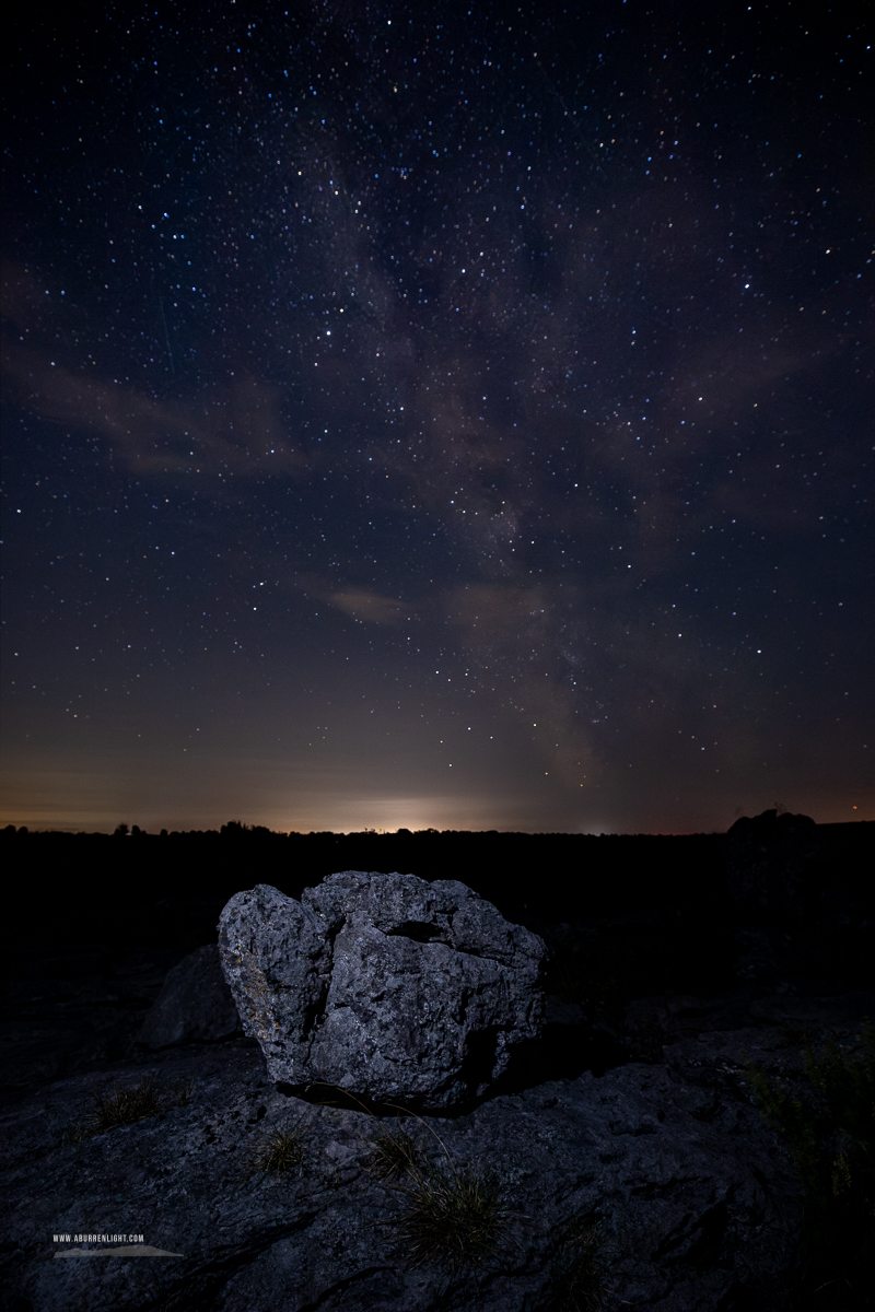 The Milky Way rises above a solitary glacial erratic on weathered limestone pavement in the Burren National Park.